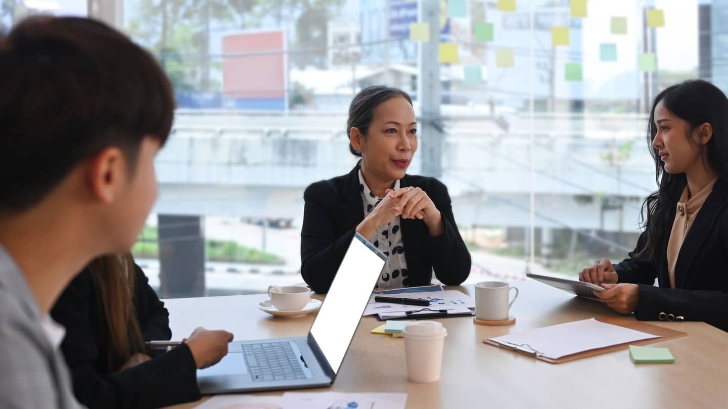 a group of people sitting at a table looking at a laptop