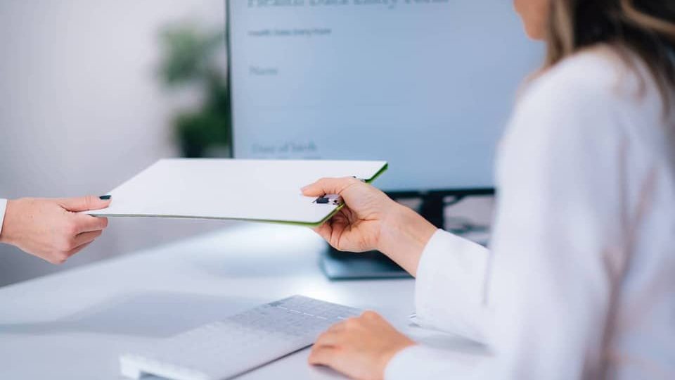 CQC solutions a woman sitting at a table using a laptop