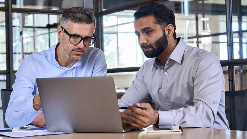 resilience support a man sitting at a table looking at a laptop